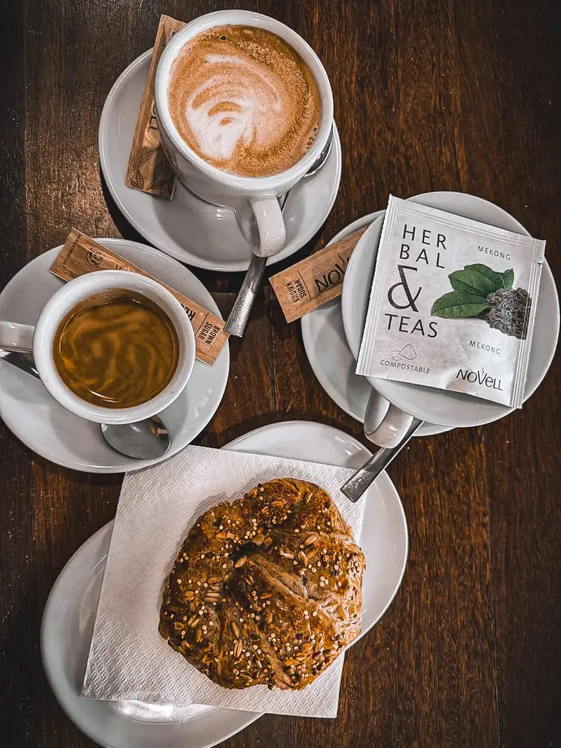 Café con leche, café solo, infusión herbal y bocadillo de pan integral con semillas en Restaurante Rebeka, Barcelona