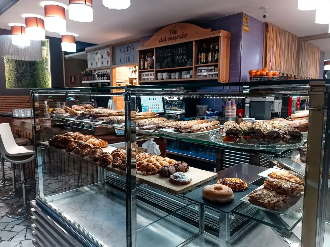Mostrador de cristal con croissants, donuts y bocadillos en la barra de Restaurante Rebeka en Barcelona, ambiente de cafetería mediterránea