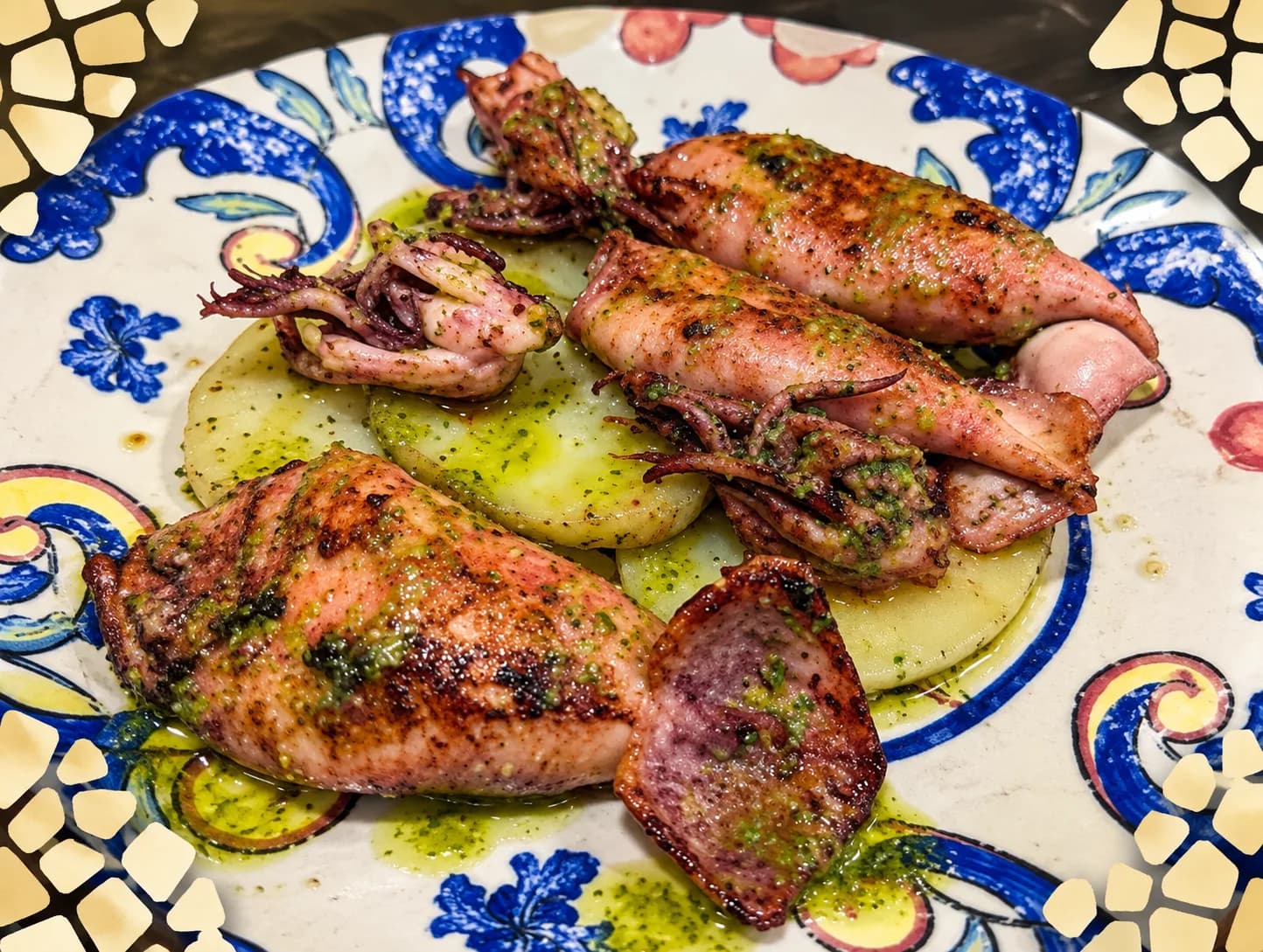 Chipirones a la plancha sobre rodajas de patata con salsa verde en un plato decorado en Rebeka, restaurante en Barcelona
